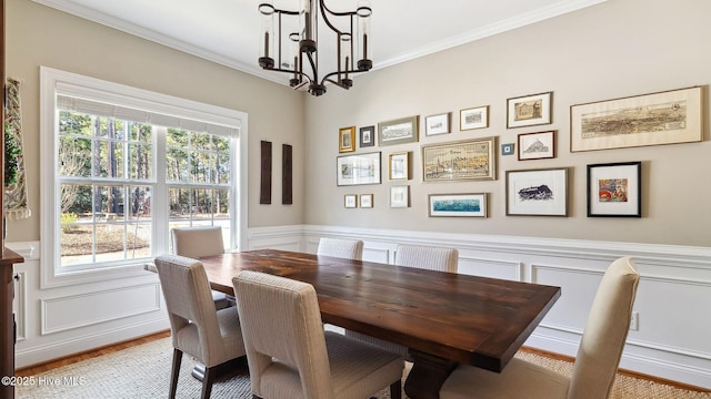 dining area with crown molding, wainscoting, and a notable chandelier