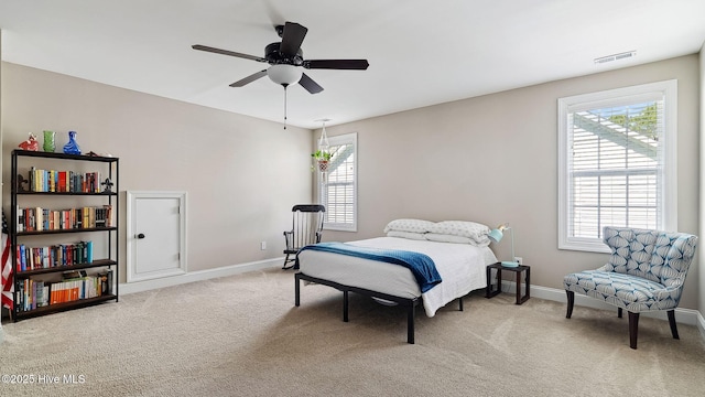 bedroom featuring baseboards, multiple windows, visible vents, and light colored carpet