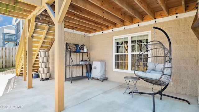 view of patio featuring fence and stairs