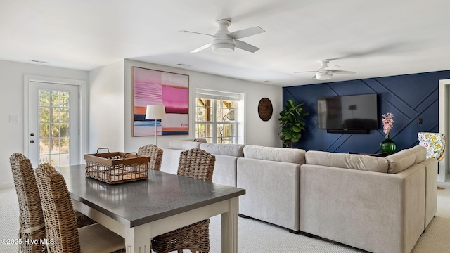 living area with carpet, ceiling fan, visible vents, and a wealth of natural light