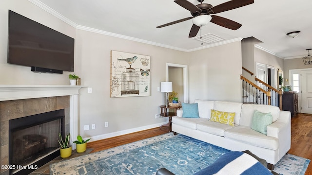 living room with baseboards, visible vents, wood finished floors, stairs, and crown molding