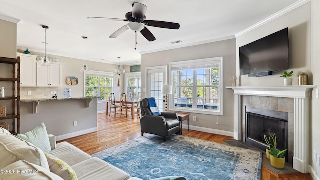 living room with baseboards, light wood-type flooring, a fireplace, and crown molding