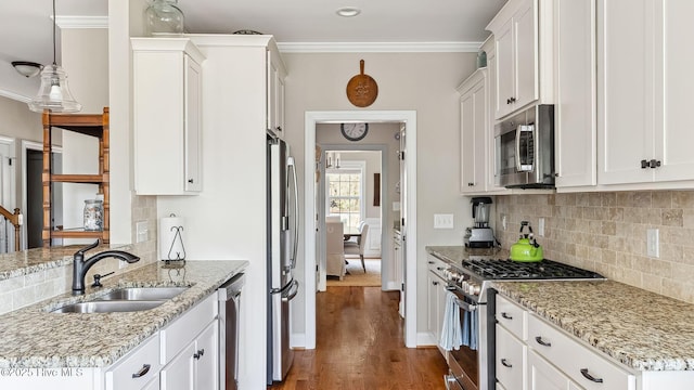 kitchen featuring stainless steel appliances, a sink, white cabinetry, and crown molding