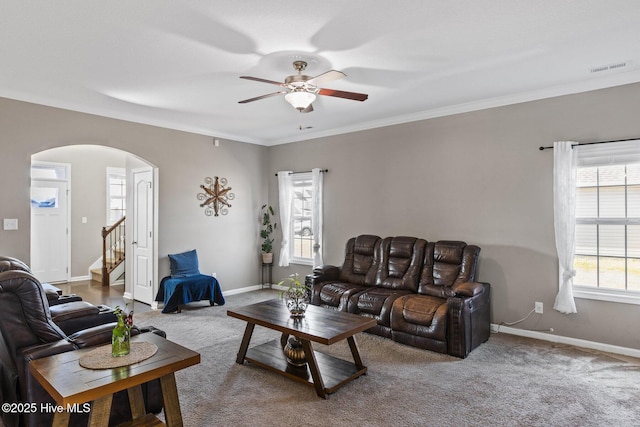 living area featuring baseboards, arched walkways, carpet, and crown molding