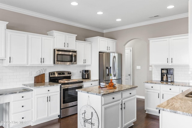 kitchen with dark wood finished floors, white cabinets, arched walkways, and stainless steel appliances