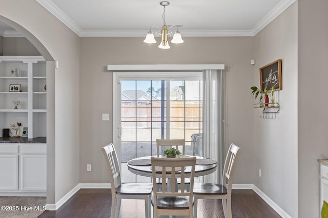 dining space with dark wood-type flooring, ornamental molding, baseboards, and a chandelier