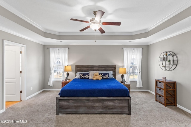 carpeted bedroom featuring a tray ceiling, a ceiling fan, baseboards, and ornamental molding