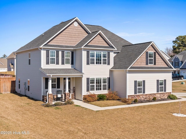 craftsman inspired home with a porch, fence, a front yard, and roof with shingles