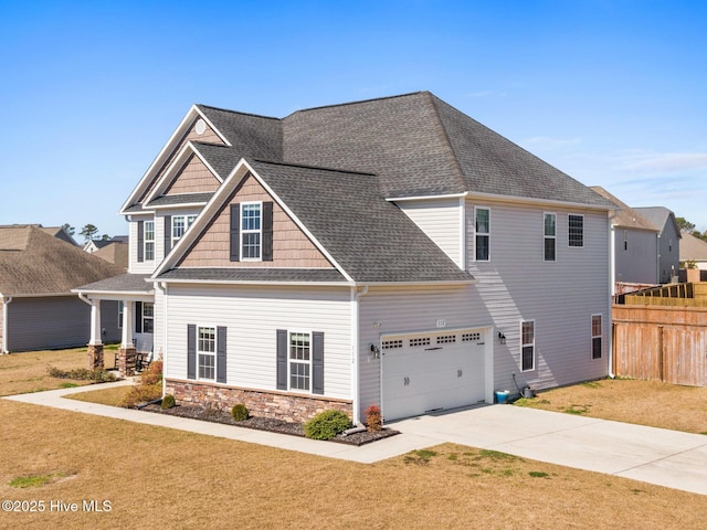 craftsman-style house with stone siding, concrete driveway, a front lawn, and fence