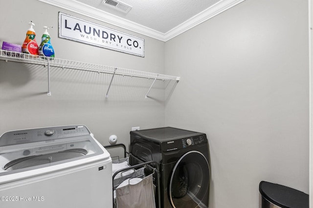 clothes washing area featuring laundry area, washing machine and dryer, crown molding, and visible vents