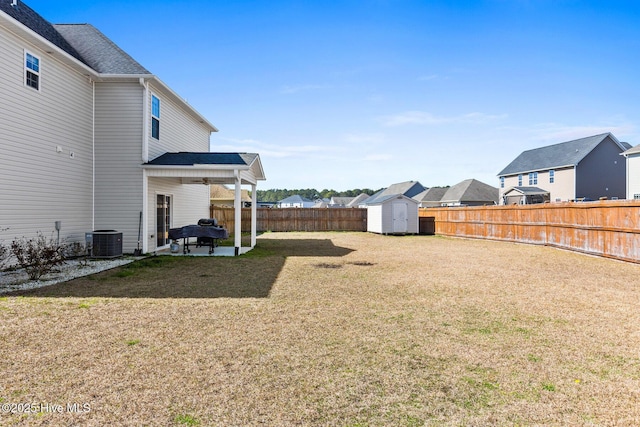 view of yard featuring cooling unit, a storage shed, a fenced backyard, an outbuilding, and a patio