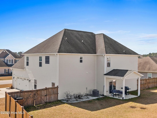 back of house with a yard, roof with shingles, a patio, and fence