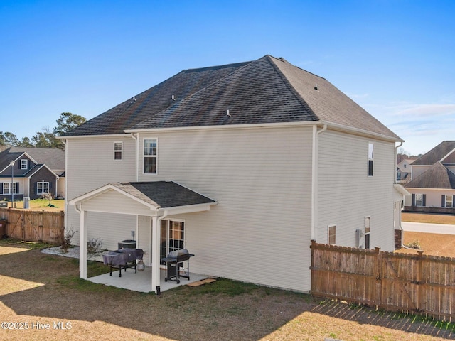 rear view of property with a patio, fence, and a shingled roof