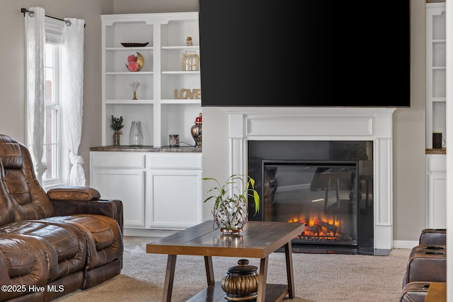 carpeted living area with a glass covered fireplace