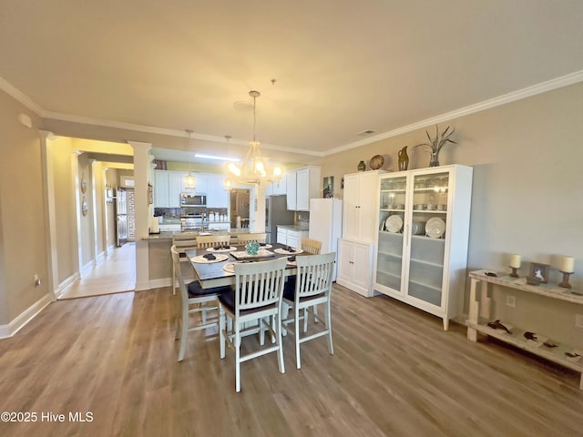 dining area with a notable chandelier, light wood-style flooring, and crown molding