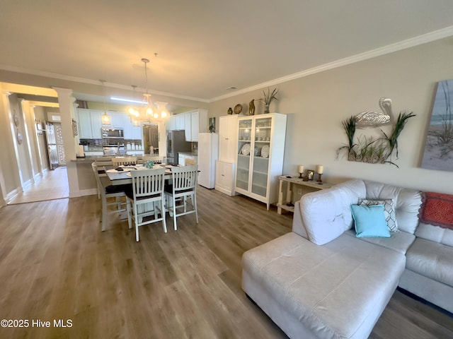 dining room with a chandelier, ornamental molding, and wood finished floors