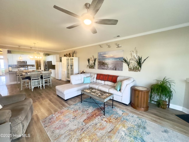 living room featuring ceiling fan, wood finished floors, visible vents, and crown molding