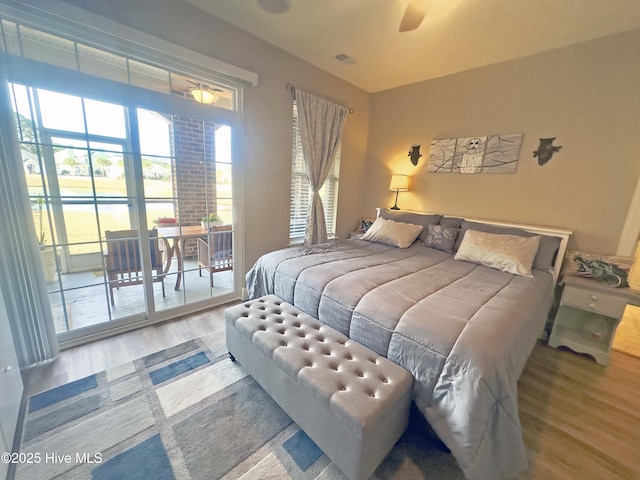 bedroom featuring access to exterior, a ceiling fan, visible vents, and wood finished floors