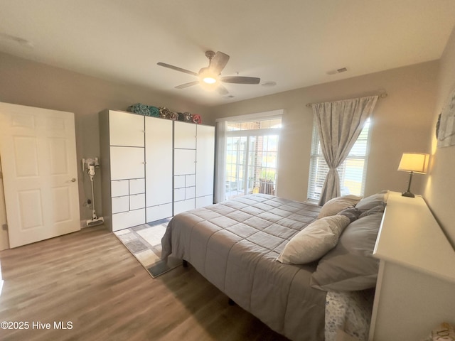 bedroom with ceiling fan, visible vents, and wood finished floors