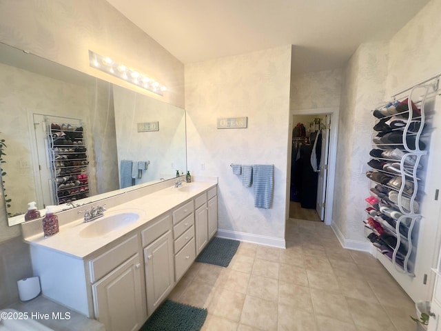 bathroom with double vanity, a spacious closet, baseboards, and a sink