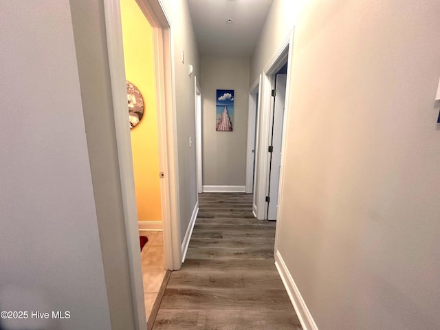 corridor with baseboards and wood finished floors