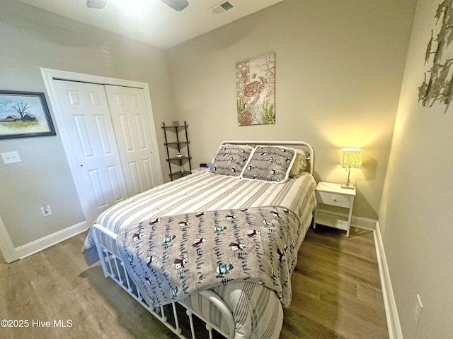 bedroom with a closet, visible vents, ceiling fan, wood finished floors, and baseboards