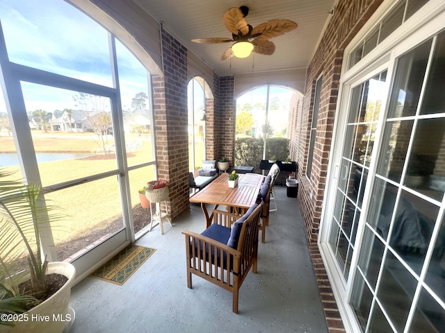 sunroom featuring a water view and a ceiling fan