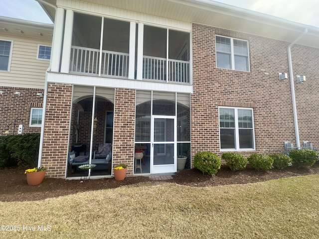 back of house with brick siding and a sunroom