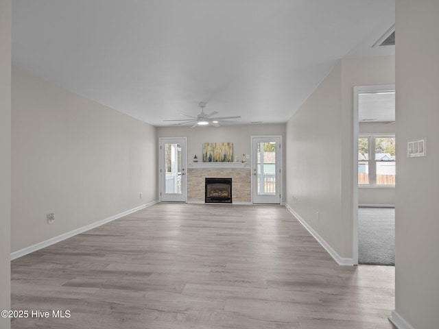 unfurnished living room with light wood-type flooring, plenty of natural light, and a tiled fireplace