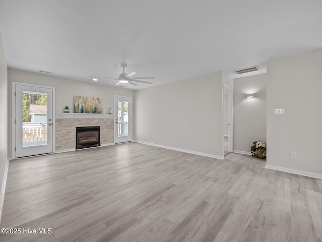 unfurnished living room featuring a ceiling fan, baseboards, visible vents, light wood-style floors, and a glass covered fireplace