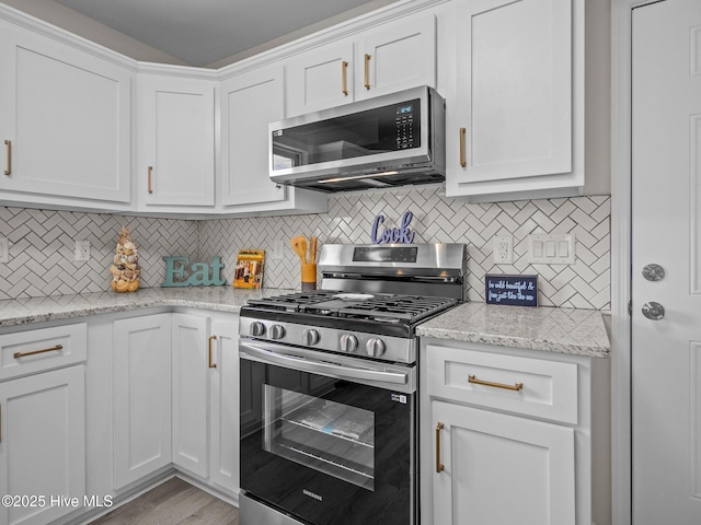 kitchen with light stone counters, appliances with stainless steel finishes, white cabinetry, and tasteful backsplash