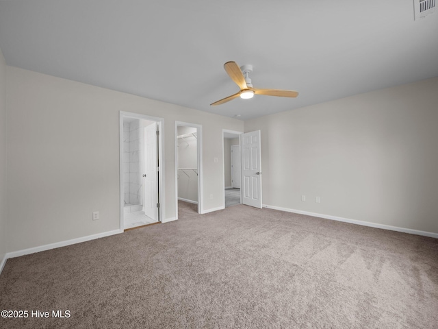 unfurnished bedroom with carpet flooring, visible vents, baseboards, a closet, and a walk in closet