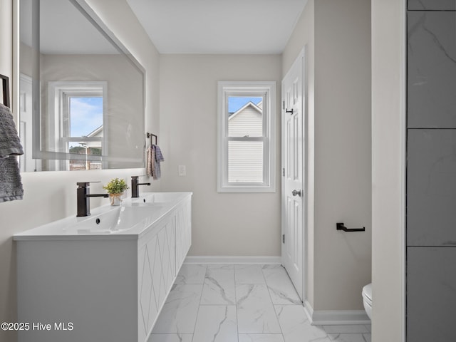 bathroom featuring marble finish floor, a healthy amount of sunlight, and a sink