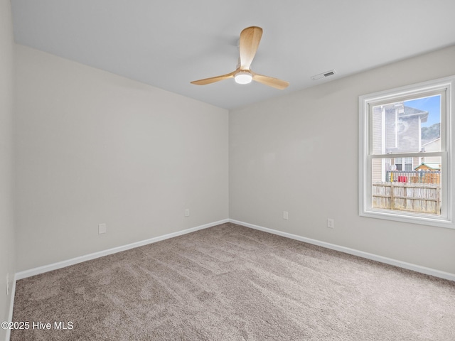 spare room featuring carpet floors, baseboards, visible vents, and a ceiling fan