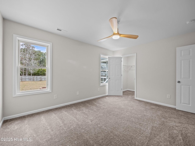 carpeted empty room featuring ceiling fan, visible vents, and baseboards