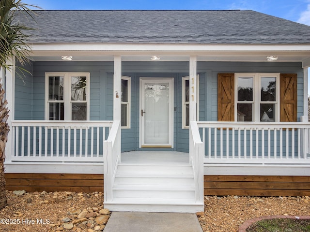 entrance to property featuring a porch and roof with shingles