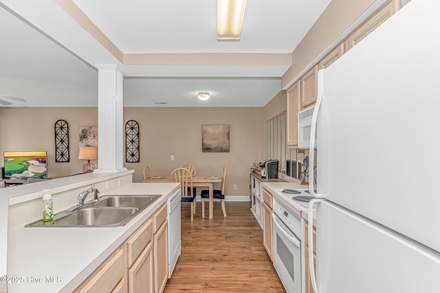 kitchen featuring white appliances, a sink, light countertops, light wood-type flooring, and decorative columns