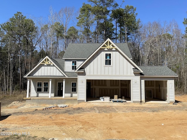 modern farmhouse style home featuring a porch, a garage, a shingled roof, dirt driveway, and board and batten siding