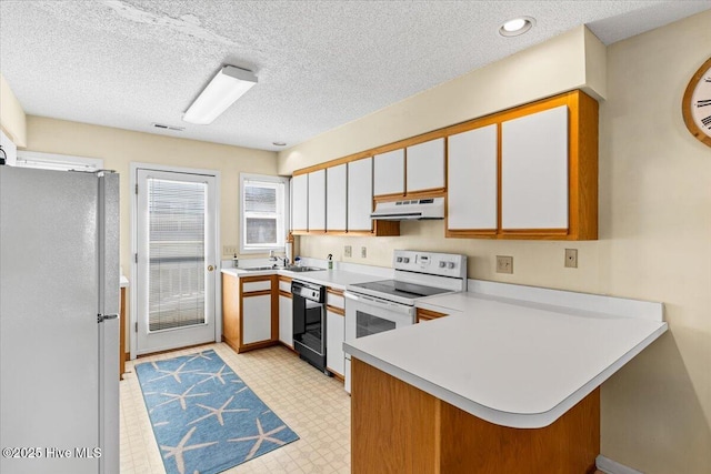 kitchen with under cabinet range hood, white appliances, a peninsula, light countertops, and light floors