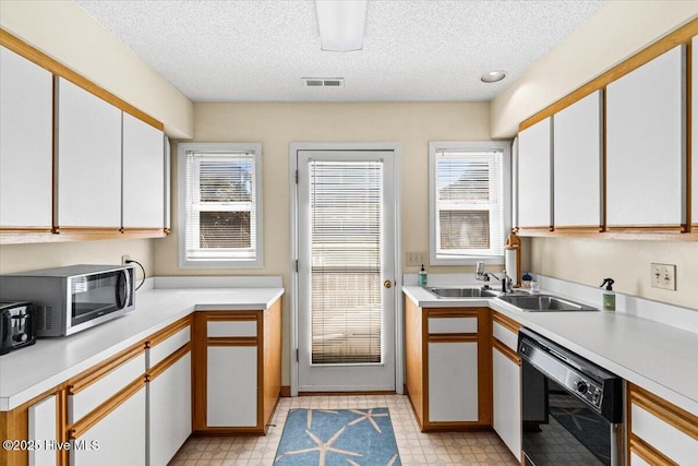 kitchen with visible vents, stainless steel microwave, light countertops, light floors, and dishwasher