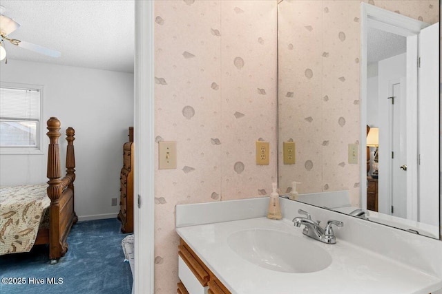 bathroom featuring vanity, a ceiling fan, wallpapered walls, and a textured ceiling
