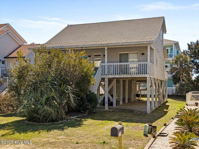 rear view of property featuring a porch, a lawn, roof with shingles, and stairway