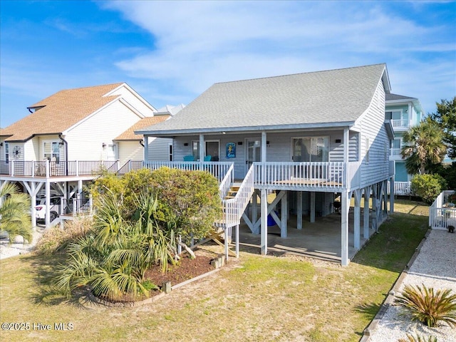 raised beach house featuring stairs, a shingled roof, a porch, and a front yard