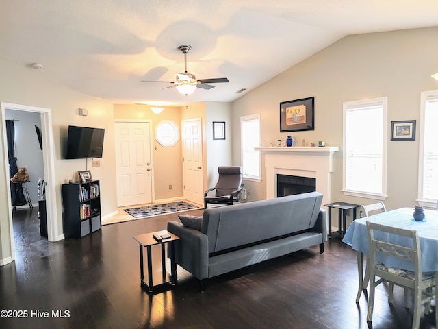 living room featuring ceiling fan, a fireplace, visible vents, vaulted ceiling, and dark wood-style floors