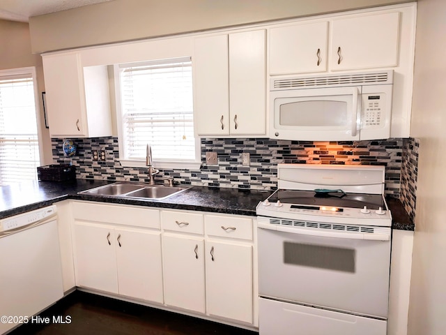 kitchen featuring white appliances, a sink, white cabinetry, decorative backsplash, and dark countertops