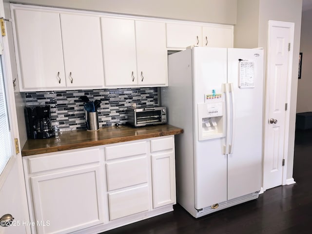 kitchen with white fridge with ice dispenser, wood counters, white cabinetry, and decorative backsplash