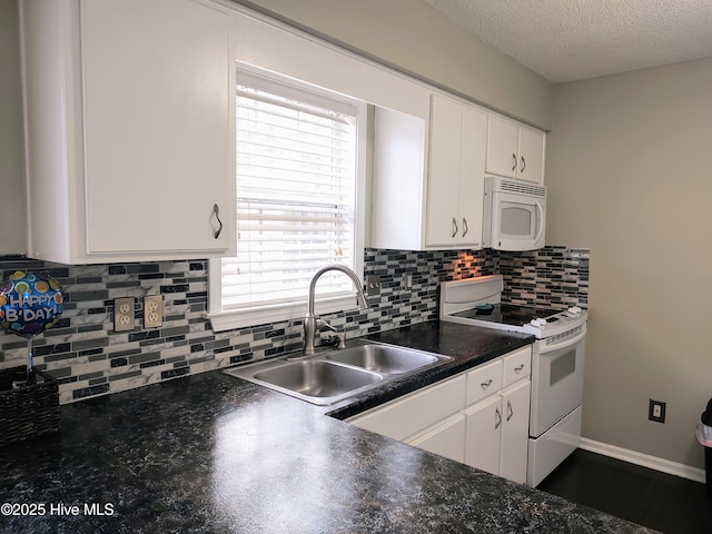 kitchen with white appliances, dark countertops, a sink, and white cabinets