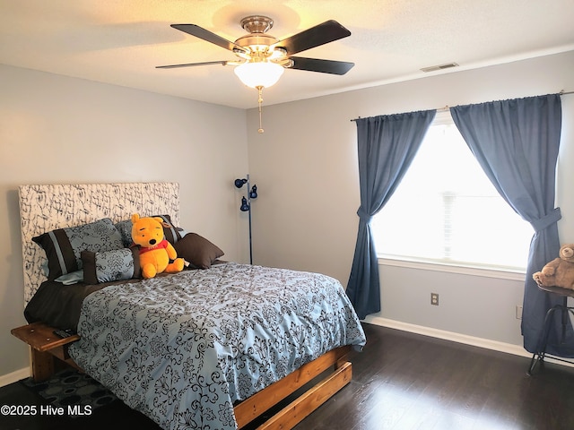 bedroom featuring visible vents, baseboards, ceiling fan, and dark wood-type flooring