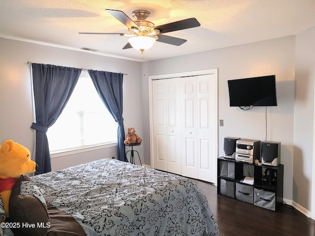 bedroom featuring a textured ceiling, visible vents, dark wood finished floors, and a closet