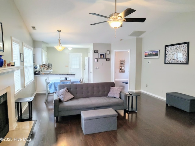 living area featuring dark wood-style flooring, visible vents, and vaulted ceiling